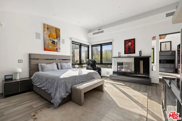 a spacious bedroom with a bed a fireplace and a flat screen tv