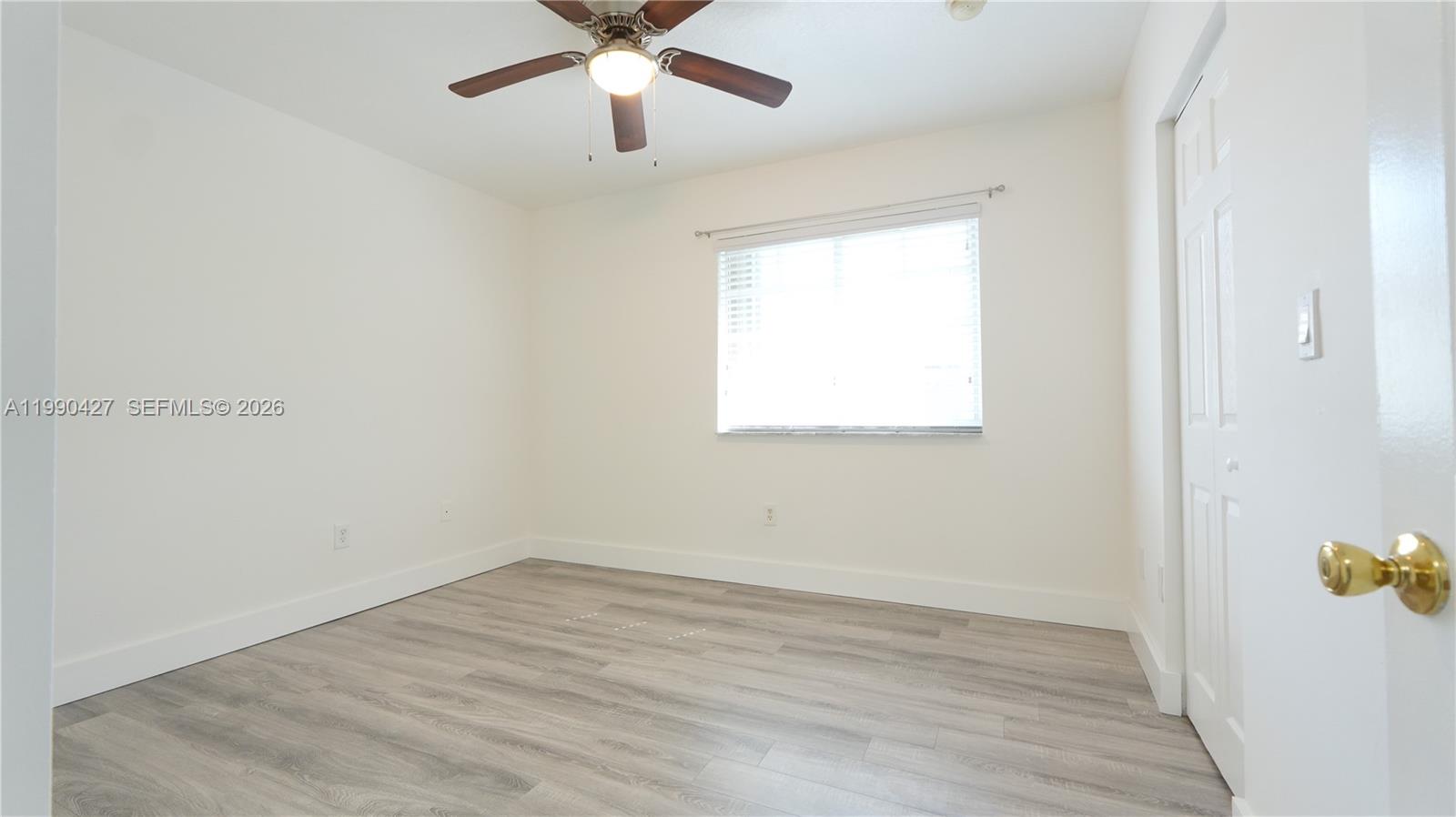 14138 Southwest 260th Street, Unit 106 Homestead, FL 33032 - Photo 6 of 12 an empty room with wooden floor and windows