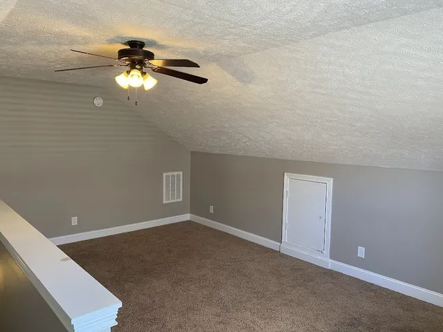 a view of a room with a hanging light and hardwood