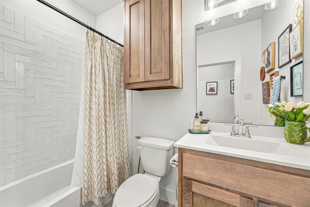 7112 Branch Road Fort Worth, TX 76179 - Photo 22 of 39 Downstairs full bathroom featuring a white subway tile shower surround in a herringbone pattern,vanity with a white countertop, and wood-finish cabinetry.
