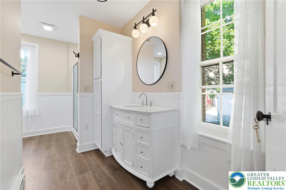4682 Steuben Road Bethlehem, PA 18020 - Photo 33 of 79 A well-lit bathroom features a white vanity, circular mirror, and hardwood flooring.