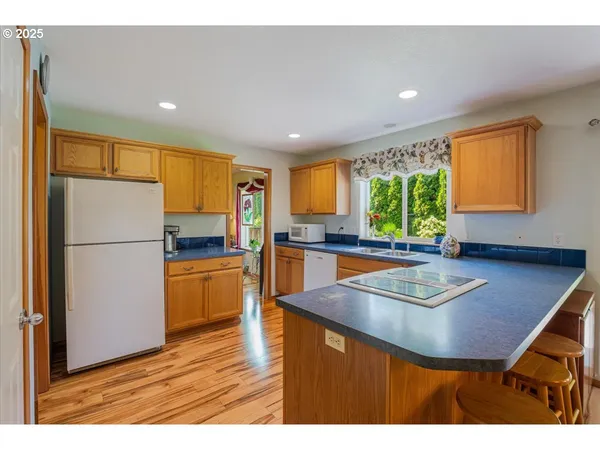 a kitchen with stainless steel appliances granite countertop sink refrigerator dining table and chairs