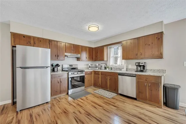 a kitchen with granite countertop a refrigerator stove top oven and sink