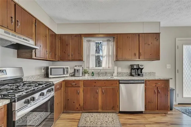 a kitchen with granite countertop wooden cabinets and a stove top oven