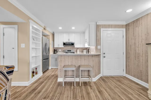 a kitchen with stainless steel appliances granite countertop a refrigerator a stove and white cabinets with wooden floor