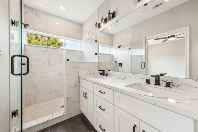 a bathroom with a double vanity sink mirror and shower
