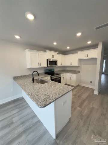 a large kitchen with stainless steel appliances granite countertop a large counter top and a stove top oven