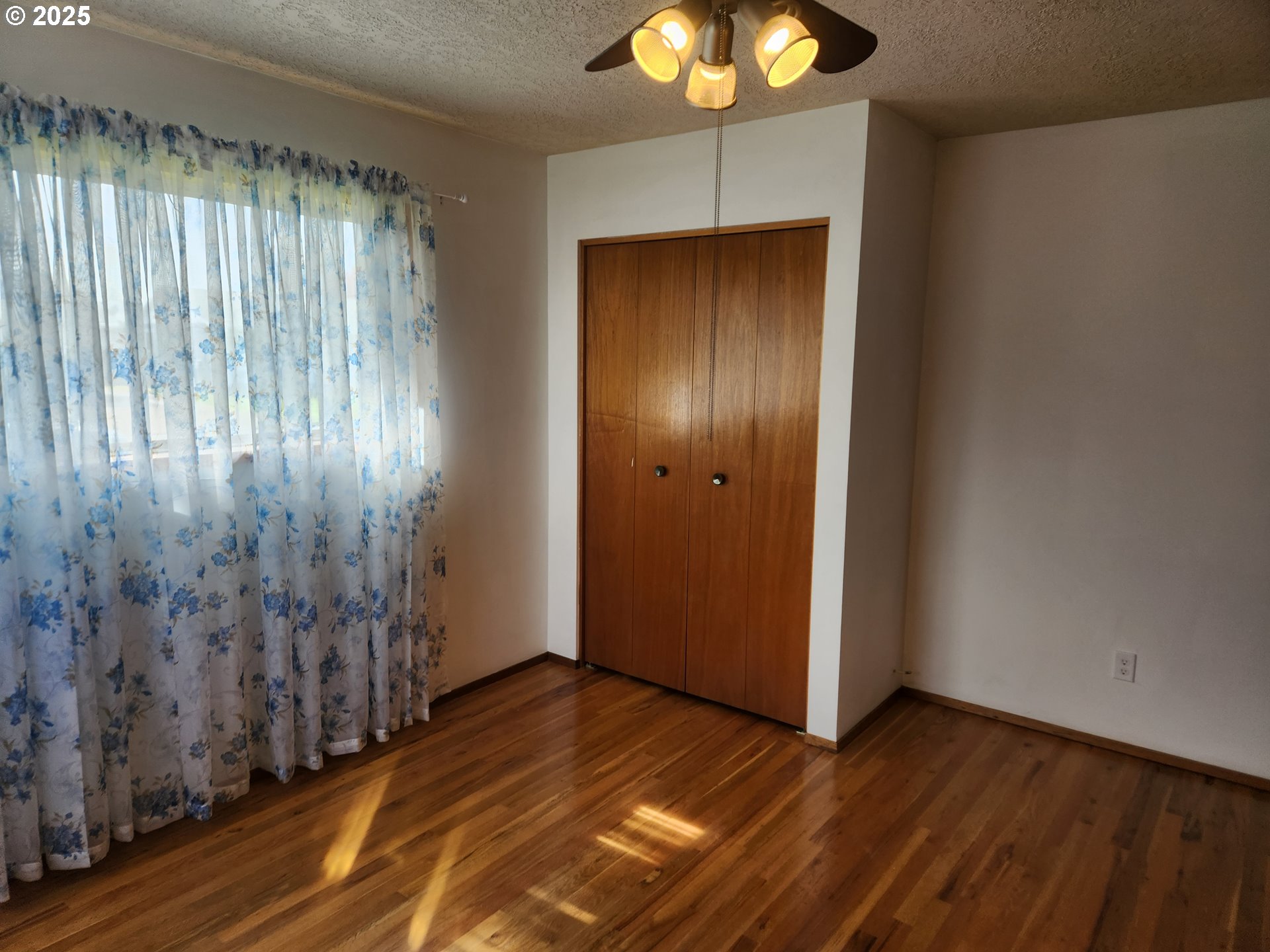 2207 Oregon Court Woodburn, OR 97071 - Photo 12 of 27 an empty room with wooden floor fan and windows