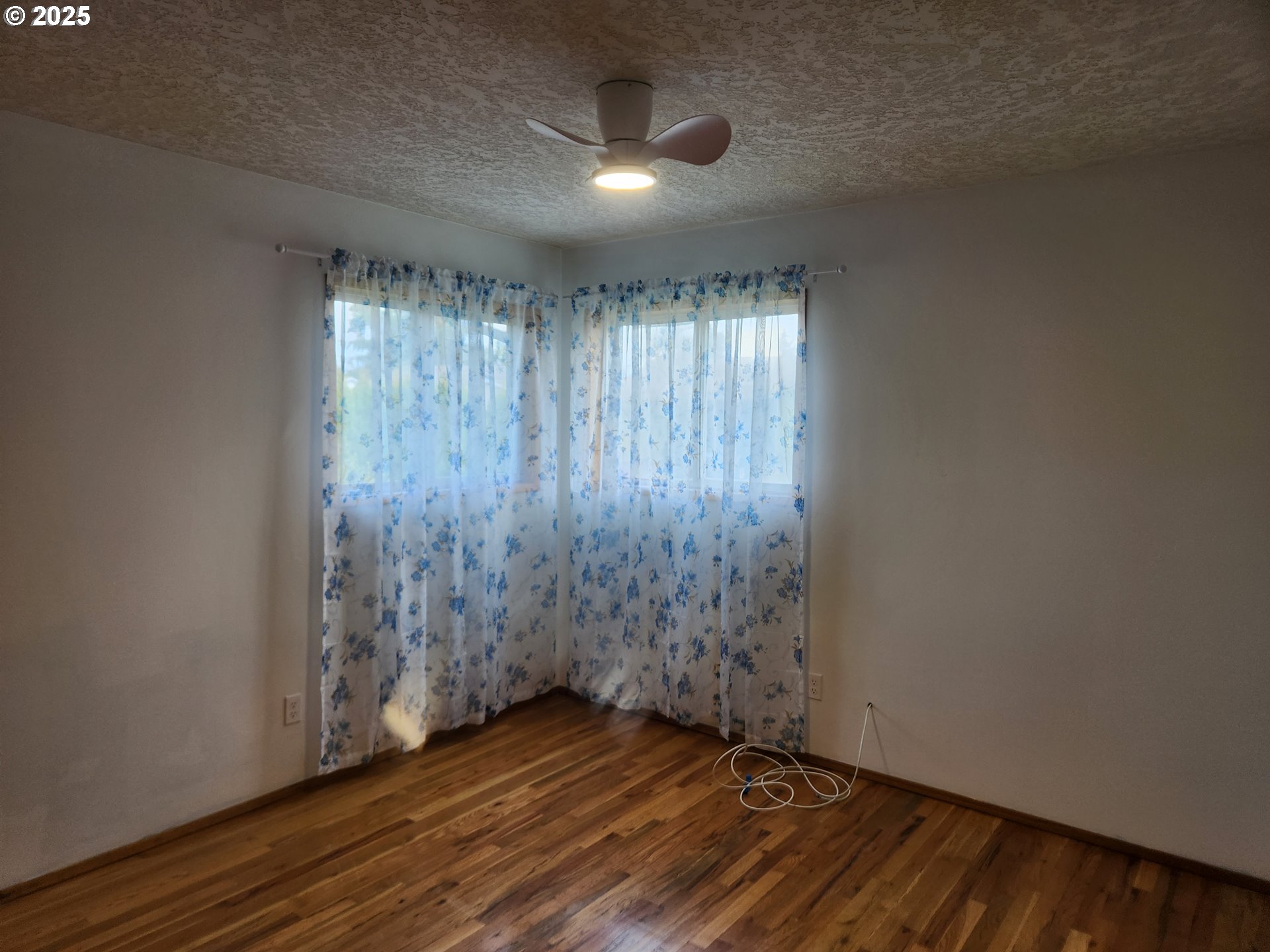 2207 Oregon Court Woodburn, OR 97071 - Photo 15 of 27 an empty room with wooden floor chandelier fan and windows