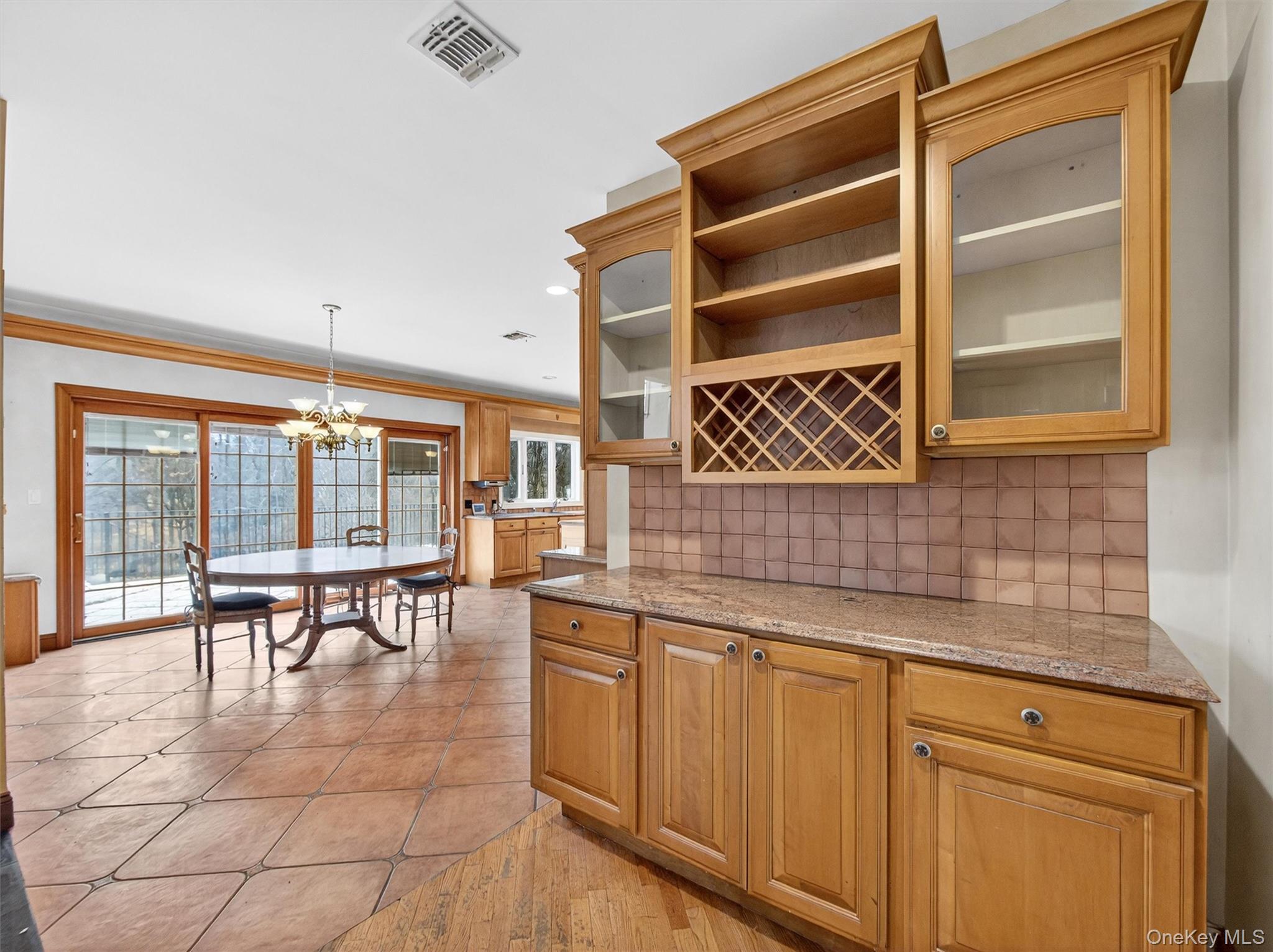 120 East Willow Tree Road Spring Valley, NY 10977 - Photo 11 of 49 Kitchen with glass insert cabinets, pendant lighting, a chandelier, ornamental molding, and light stone counters