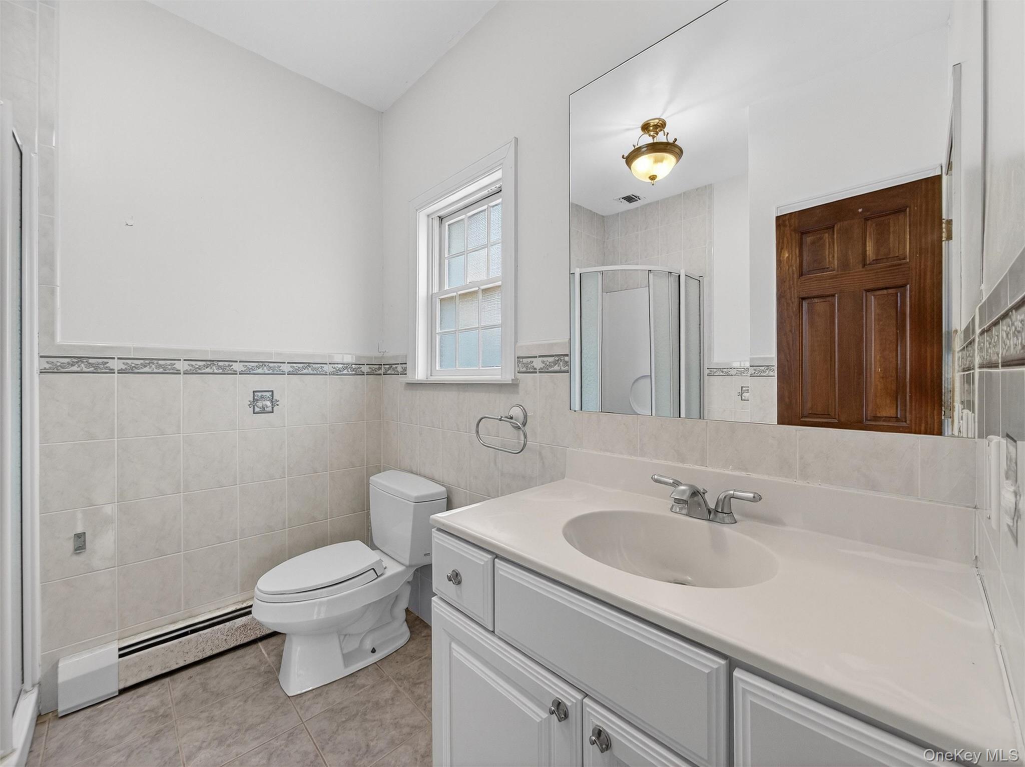 120 East Willow Tree Road Spring Valley, NY 10977 - Photo 16 of 49 Full bath with a stall shower, vanity, a baseboard radiator, tile walls, and light tile patterned floors