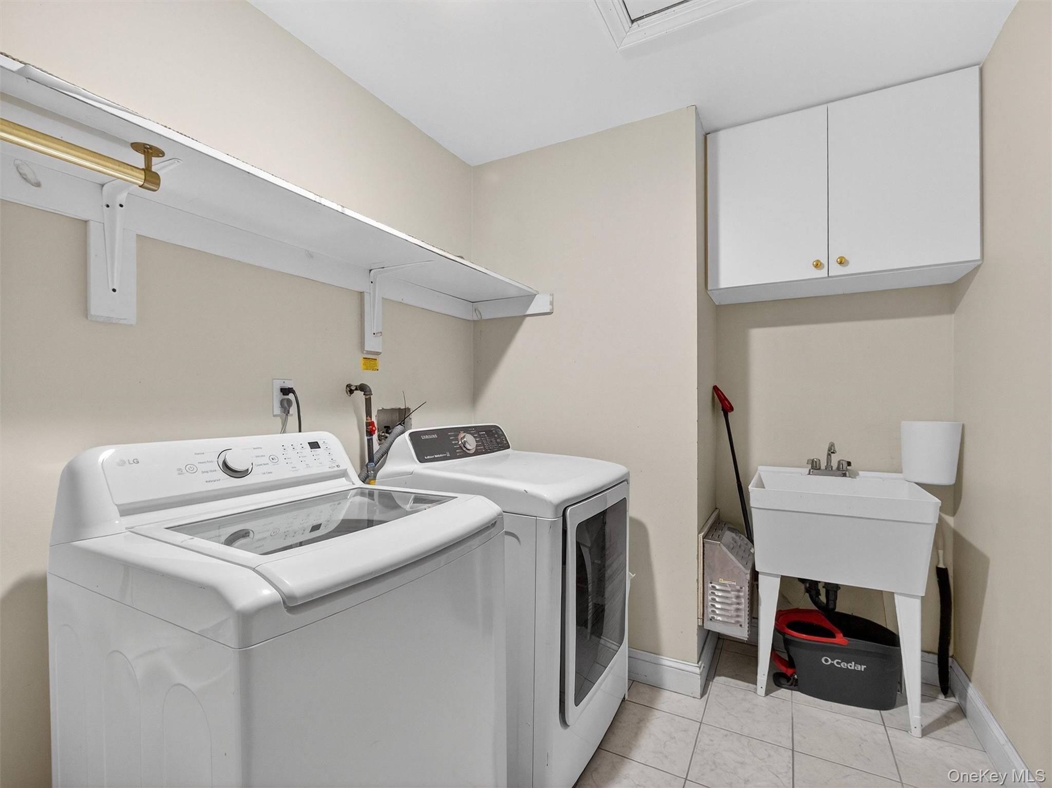 120 East Willow Tree Road Spring Valley, NY 10977 - Photo 17 of 49 Laundry room with light tile patterned floors, washing machine and dryer, and cabinet space
