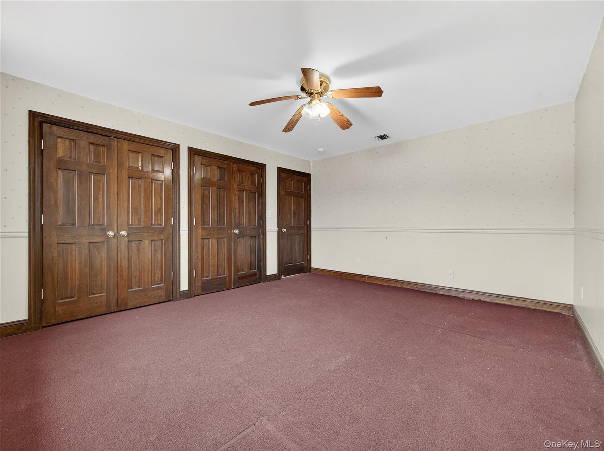 120 East Willow Tree Road Spring Valley, NY 10977 - Photo 27 of 49 Unfurnished bedroom featuring multiple closets, wallpapered walls, ceiling fan, and carpet floors