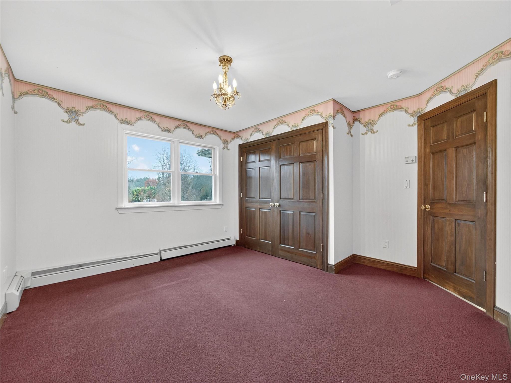 120 East Willow Tree Road Spring Valley, NY 10977 - Photo 28 of 49 Unfurnished bedroom featuring carpet, a chandelier, a baseboard heating unit, and a closet