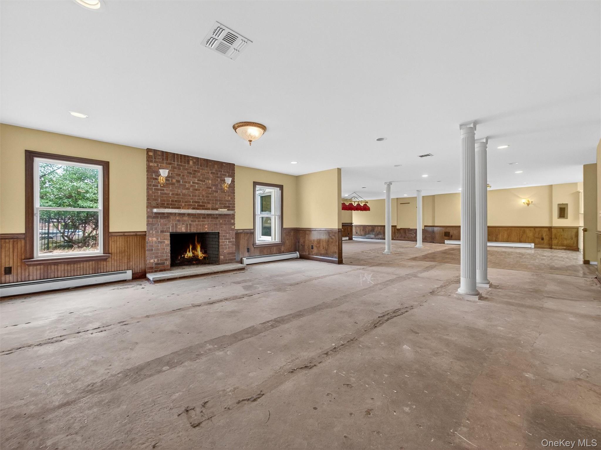 120 East Willow Tree Road Spring Valley, NY 10977 - Photo 33 of 49 Unfurnished living room with a wainscoted wall, a fireplace, wood walls, a baseboard heating unit, and recessed lighting