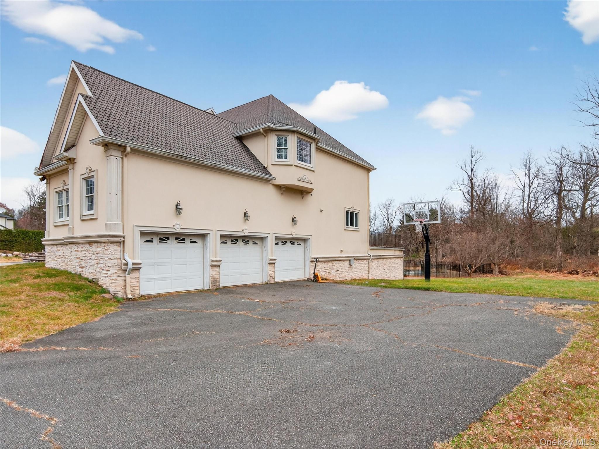 120 East Willow Tree Road Spring Valley, NY 10977 - Photo 41 of 49 View of property exterior with stucco siding, driveway, stone siding, and a lawn