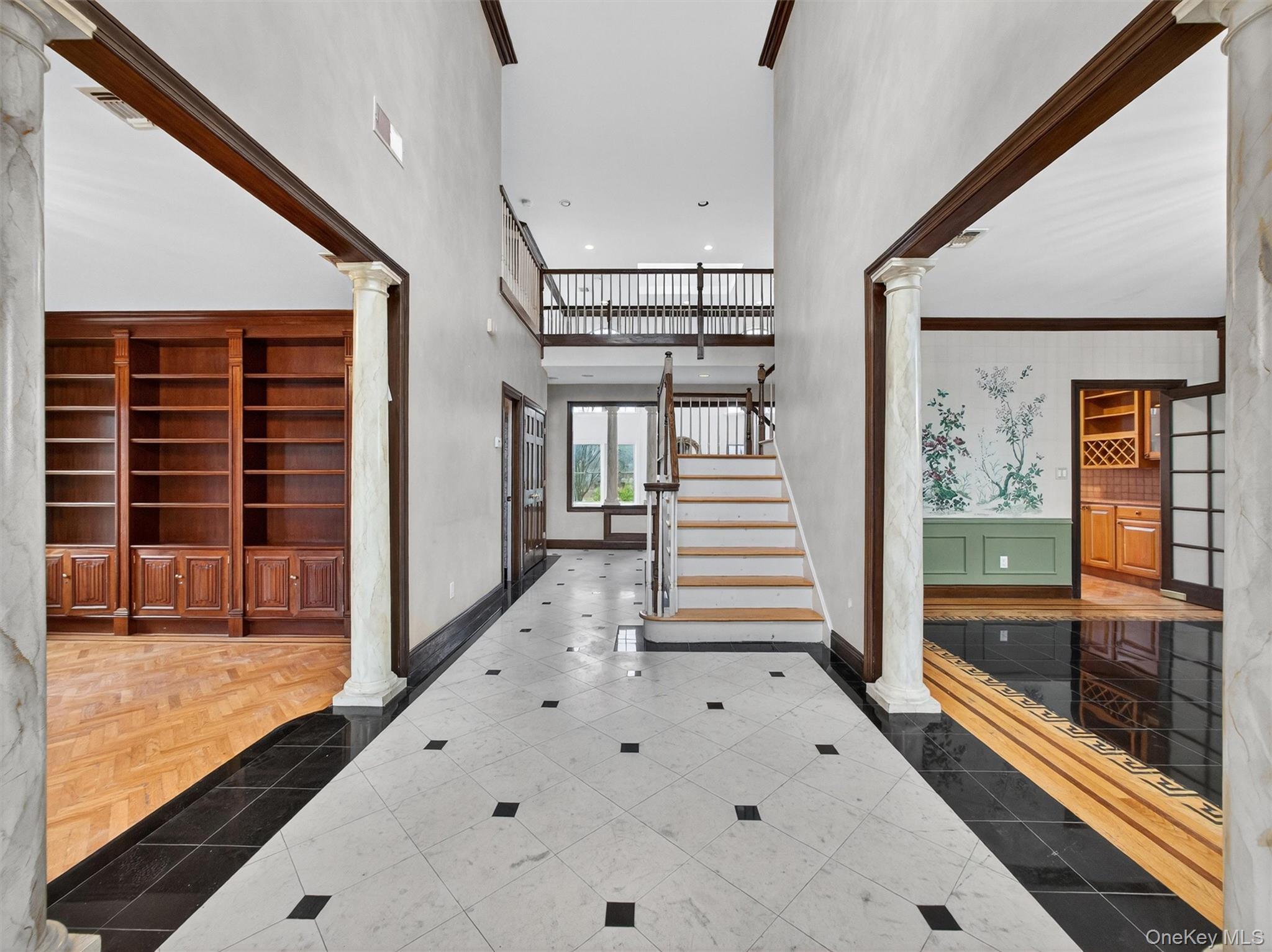 120 East Willow Tree Road Spring Valley, NY 10977 - Photo 5 of 49 Tiled entryway featuring decorative columns, a towering ceiling, inlaid floor details, stairway, and a wainscoted wall