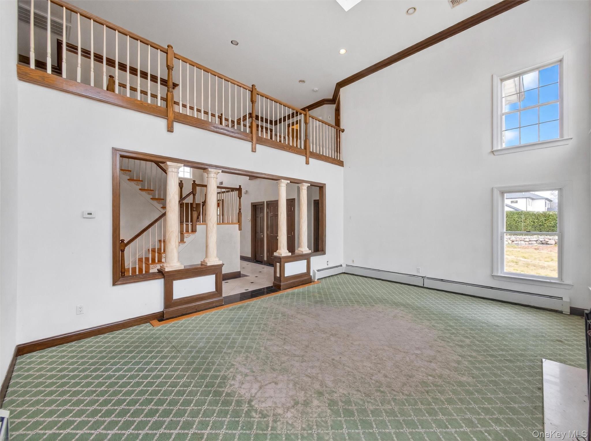 120 East Willow Tree Road Spring Valley, NY 10977 - Photo 10 of 49 Unfurnished living room featuring a high ceiling, carpet flooring, a baseboard radiator, crown molding, and ornate columns