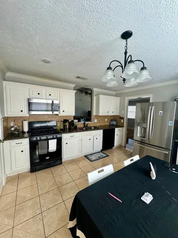 a kitchen with stainless steel appliances granite countertop a sink dishwasher stove and white cabinets with wooden floor
