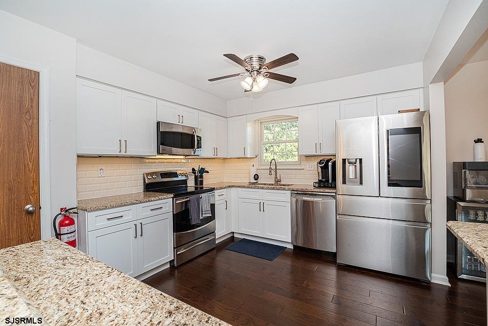68 Defeo Lane Somers Point, NJ 08244 - Photo 4 of 44 a kitchen with granite countertop a refrigerator oven a sink dishwasher and white cabinets with wooden floor