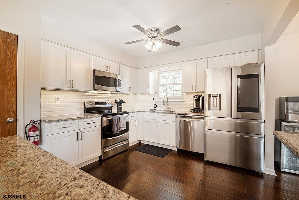 68 Defeo Lane Somers Point, NJ 08244 - Photo 6 of 44 a kitchen with granite countertop a refrigerator oven a sink dishwasher and a stove top oven with wooden floor