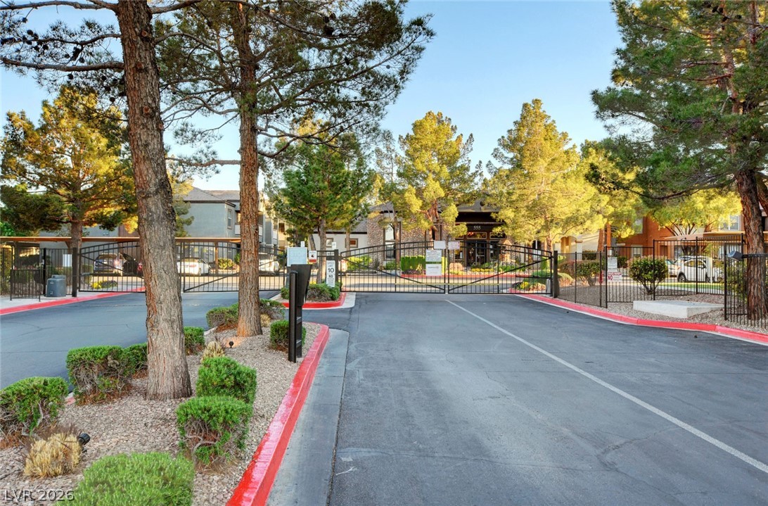 555 East Silverado Ranch Boulevard, Unit 2124 Las Vegas, NV 89183 - Photo 47 of 47 Secure community entrance with well-maintained landscaping and mature trees, offering controlled access.