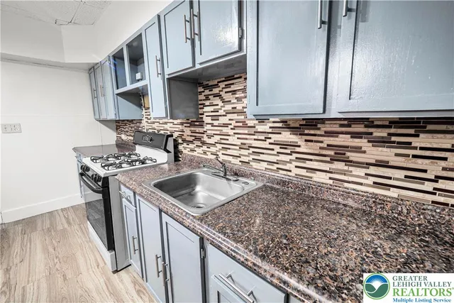 a kitchen with stainless steel appliances granite countertop a refrigerator a stove and a sink with wooden cabinets