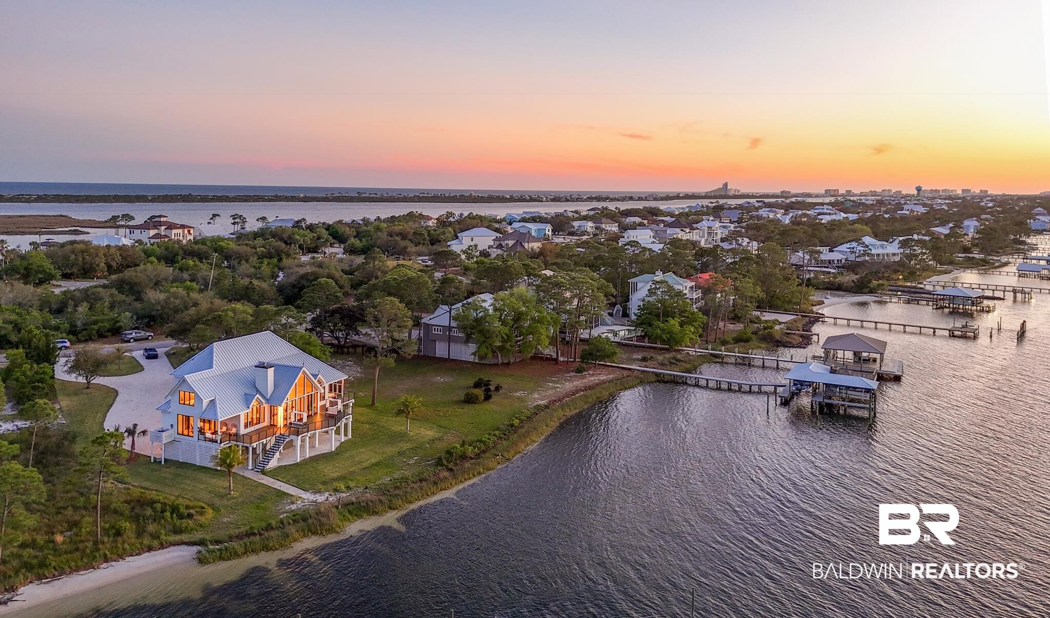 33349 River Road Orange Beach, AL 36561 - Photo 8 of 61 Waterfront property featuring a prominent residence with a metal roof, multiple balconies, and a private boat dock with a covered slip