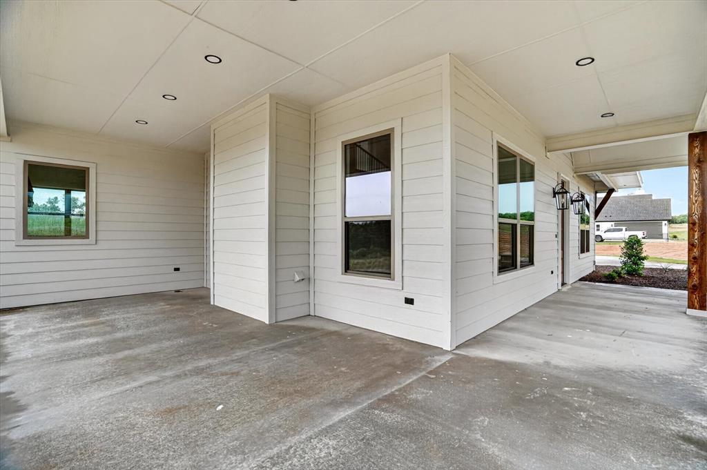225 Kilkenny Road Poolville, TX 76487 - Photo 30 of 36 Covered patio featuring a concrete surface, white horizontal siding, recessed ceiling lighting, and exterior wall sconces