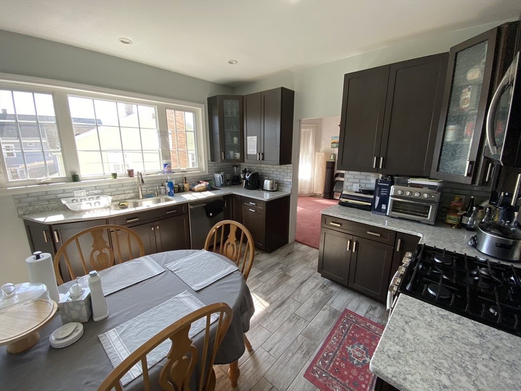 55 Cherry Street, Unit 55 Medford, MA 02155 - Photo 6 of 9 a kitchen with a stove a sink a dining table and chairs