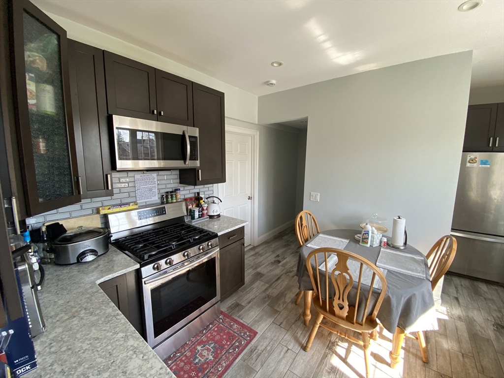 55 Cherry Street, Unit 55 Medford, MA 02155 - Photo 7 of 9 a kitchen with granite countertop a stove and a wooden floor