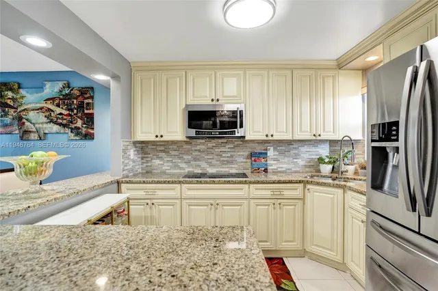 a kitchen with stainless steel appliances granite countertop a refrigerator sink and microwave