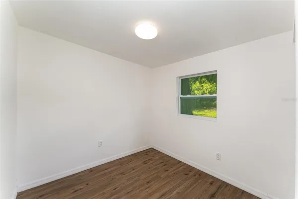 a view of an empty room with window and wooden floor