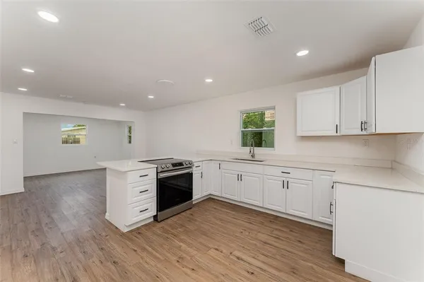 a kitchen with granite countertop a stove top oven sink and cabinets