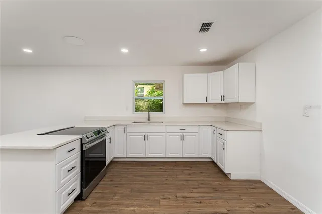 a large kitchen with granite countertop a stove top oven sink and cabinets