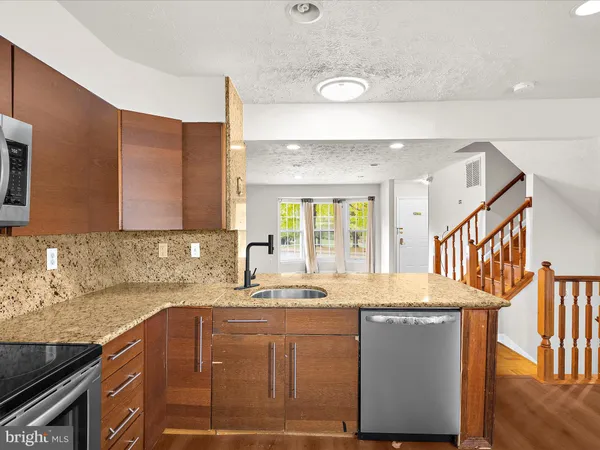 a kitchen with granite countertop a sink a stove and cabinets