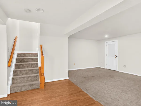 a view of an empty room with wooden floor and stairs