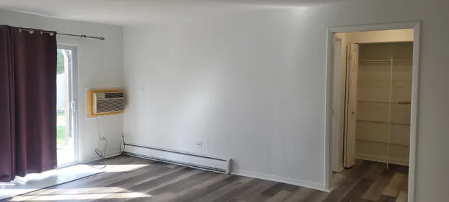 an empty room with wooden floor and a bathroom