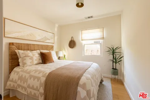 a bedroom with a large bed and a potted plant