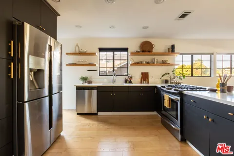 a kitchen with stainless steel appliances granite countertop a refrigerator a sink dishwasher a stove and a refrigerator