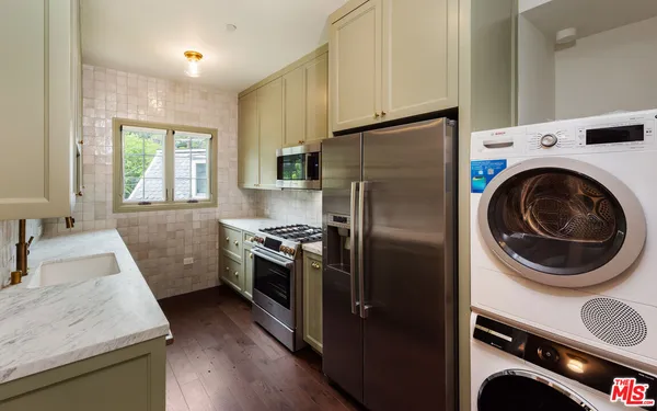 a kitchen with granite countertop a refrigerator a sink a stove and washer