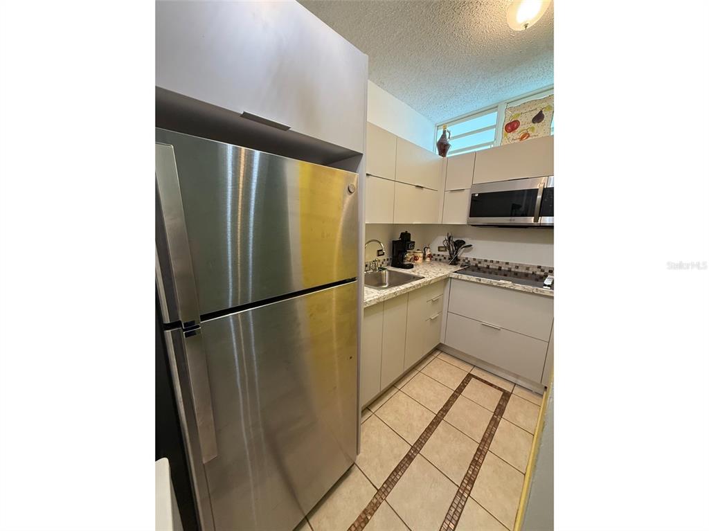 Condo Pelican Reef Condo Pelican Reef, Unit 302 Rincon, PR 00677 - Photo 14 of 16 a kitchen with stainless steel appliances a refrigerator sink and stove