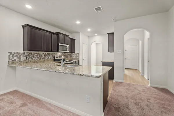 a kitchen with stainless steel appliances granite countertop a sink a stove and a refrigerator
