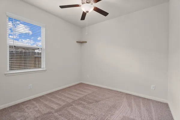an empty room with a window and a fan