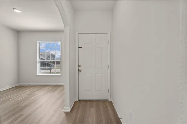 a view of hallway with window and wooden floor