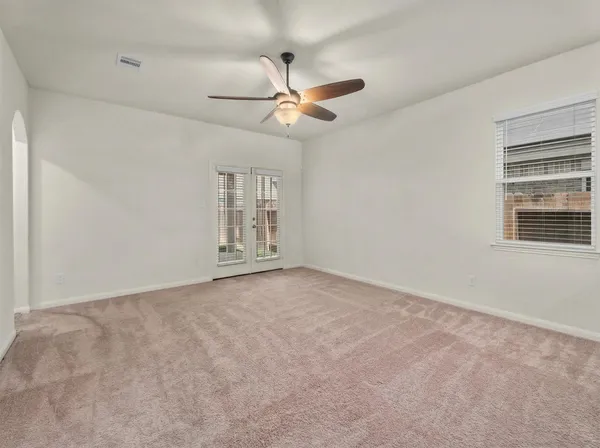 an empty room with windows and fan