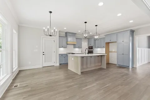 a large kitchen with white cabinets and wooden floor
