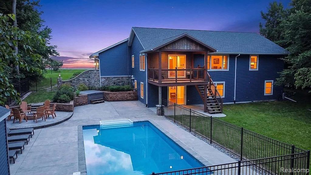 1555 Thompson Road Bad Axe, MI 48413 - Photo 2 of 14 Backyard featuring an in-ground swimming pool, expansive concrete patio, and a elevated deck with a wood-finish railing