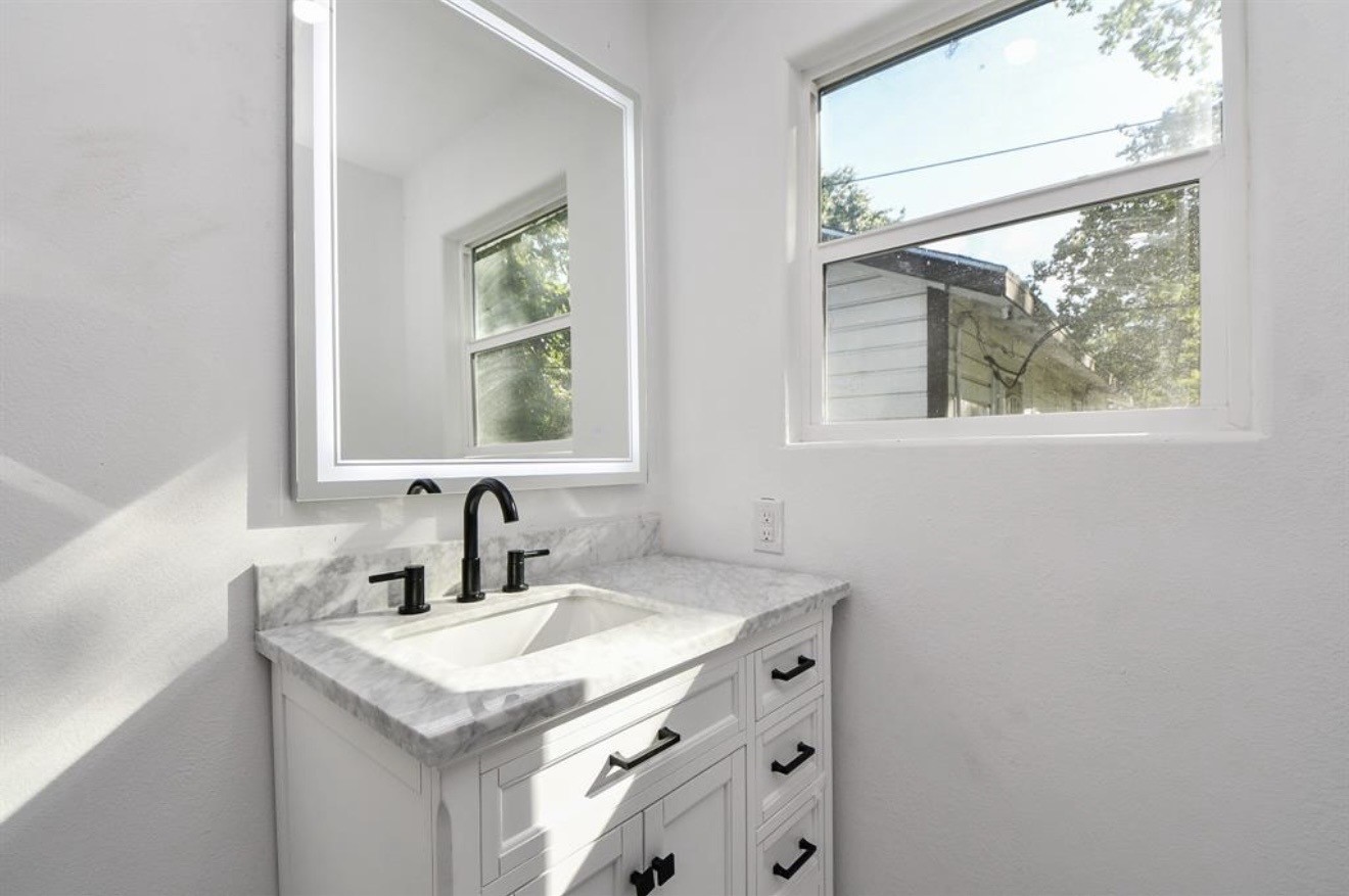 6834 St Augustine Street Houston, TX 77021 - Photo 11 of 21 a bathroom with a granite countertop sink a mirror and a window