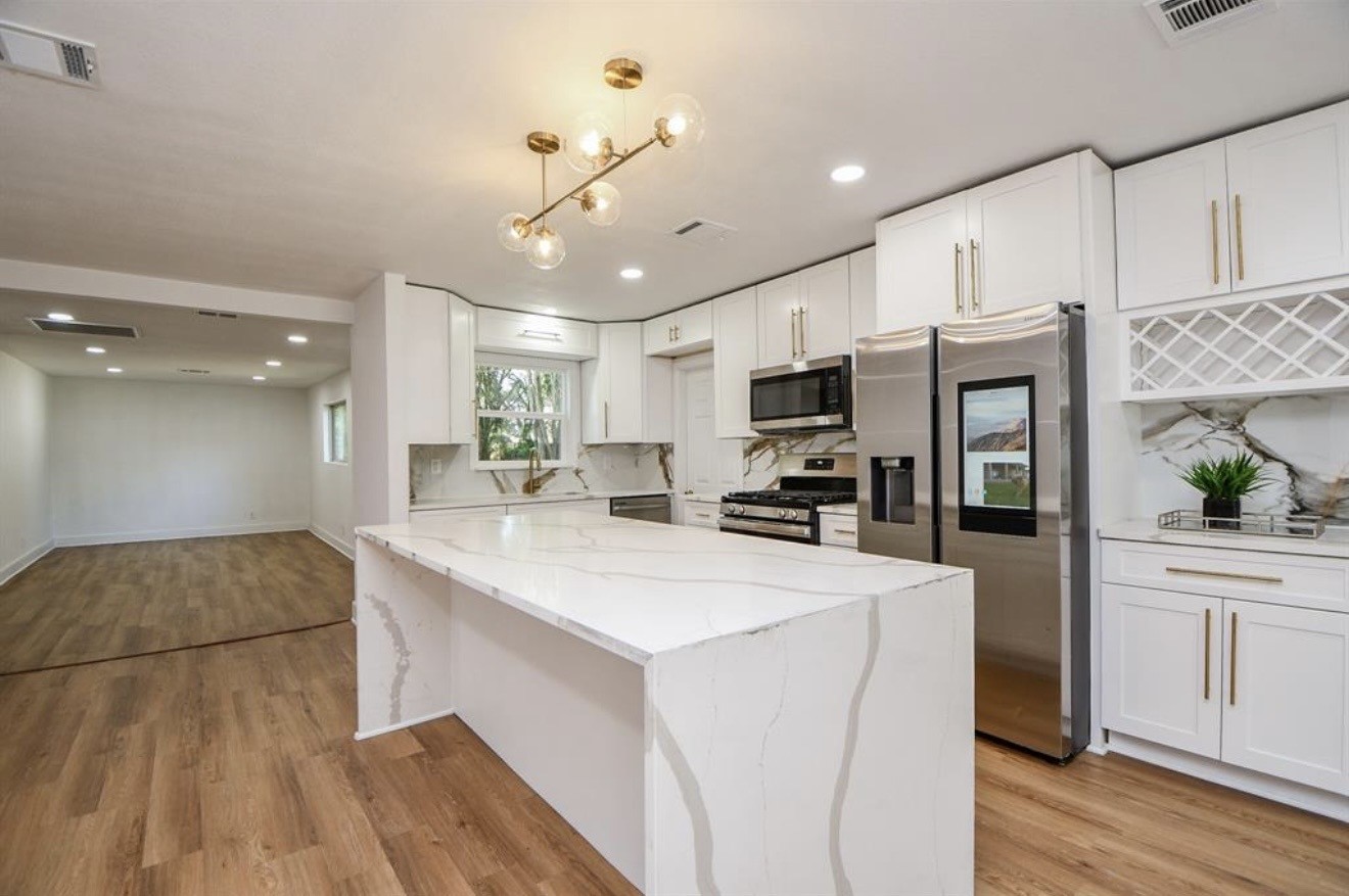 6834 St Augustine Street Houston, TX 77021 - Photo 2 of 21 a large white kitchen with a refrigerator a stove top oven a sink dishwasher and white cabinets with wooden floor